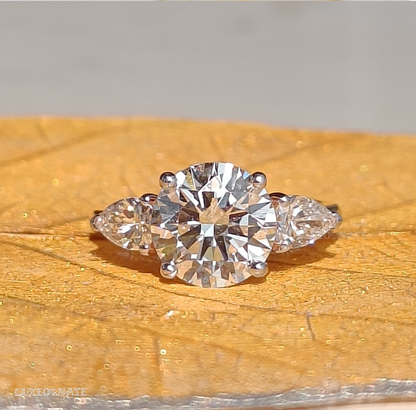 round cut three stone diamond engagement ring with pear side diamonds in white gold bridal jewelry, gifting jewelry.