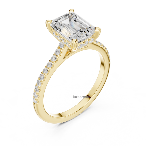 Angled view of yellow gold emerald cut diamond ring with pavé band and refined prong setting