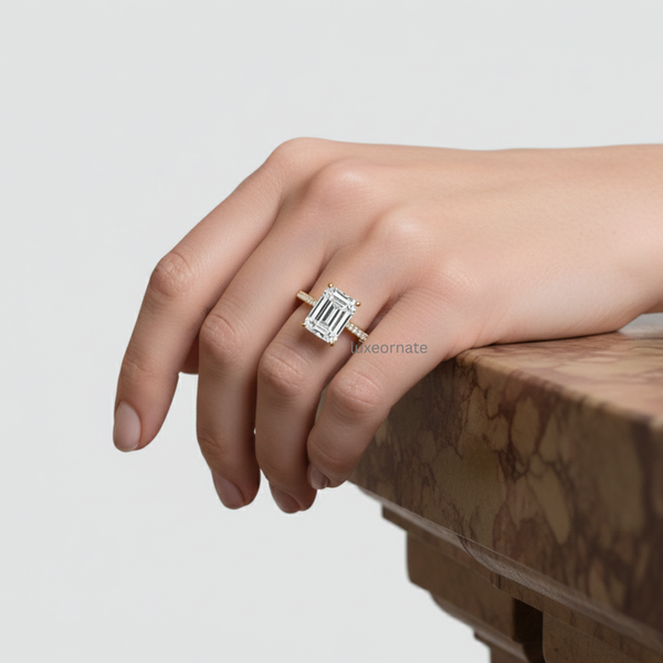 Emerald cut diamond engagement ring on hand featuring pavé band in yellow gold, lifestyle close-up