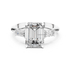 White gold emerald cut diamond engagement ring with trapezoid side diamonds, three stone lab grown bridal ring, modern fine jewelry.